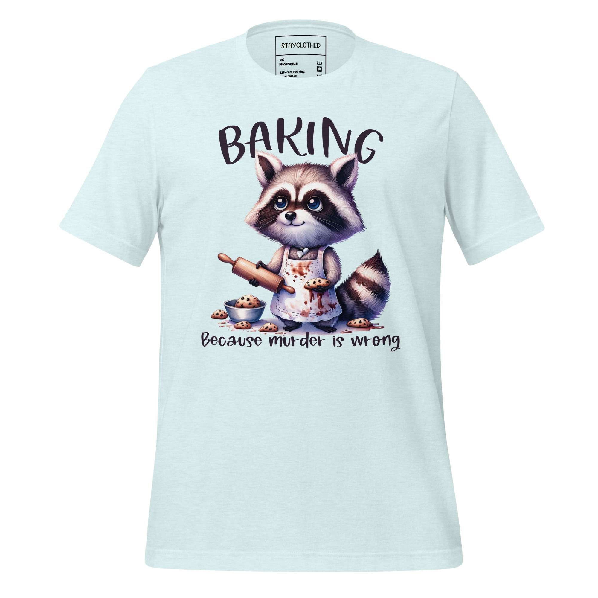 White t-shirt with a raccoon graphic and 'Baking' text on a wooden surface, featuring the brand 'StayClothed'.