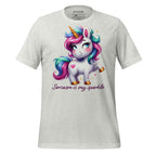 White t-shirt with a colorful unicorn graphic and text on a wooden surface, featuring the brand 'StayClothed'.