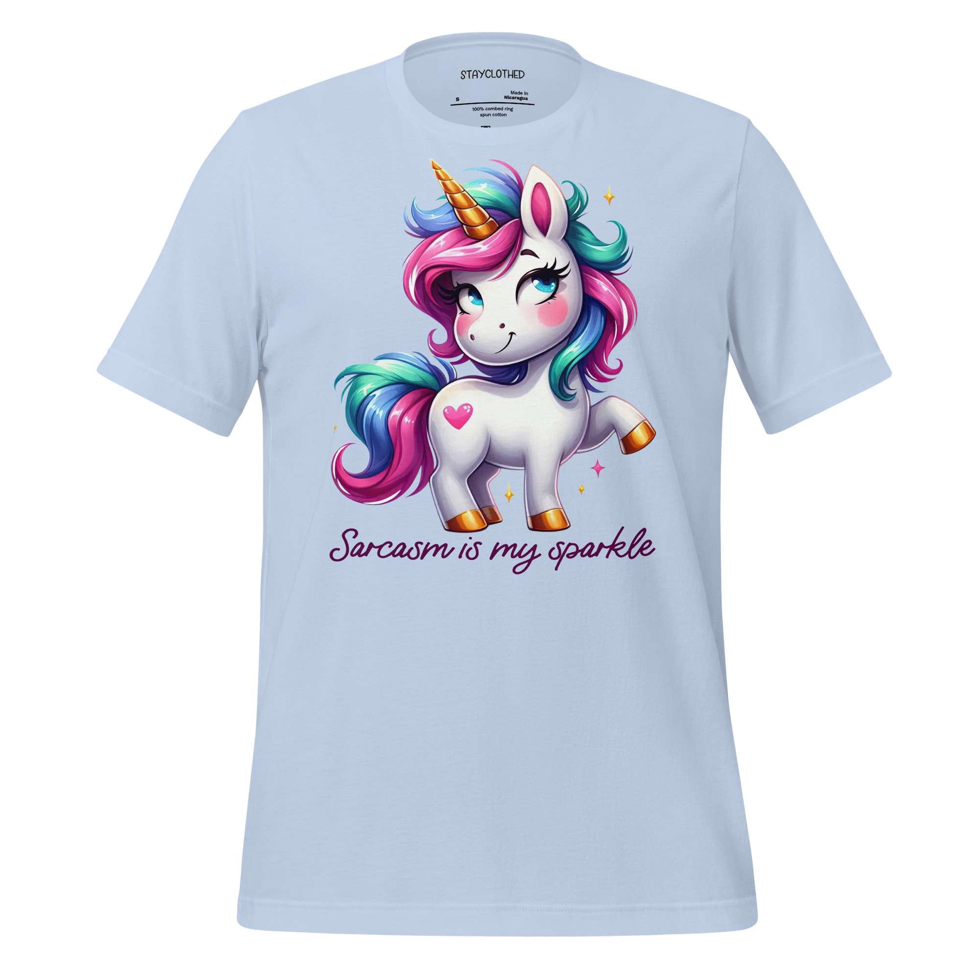 White t-shirt with a colorful unicorn graphic and text on a wooden surface, featuring the brand 'StayClothed'.