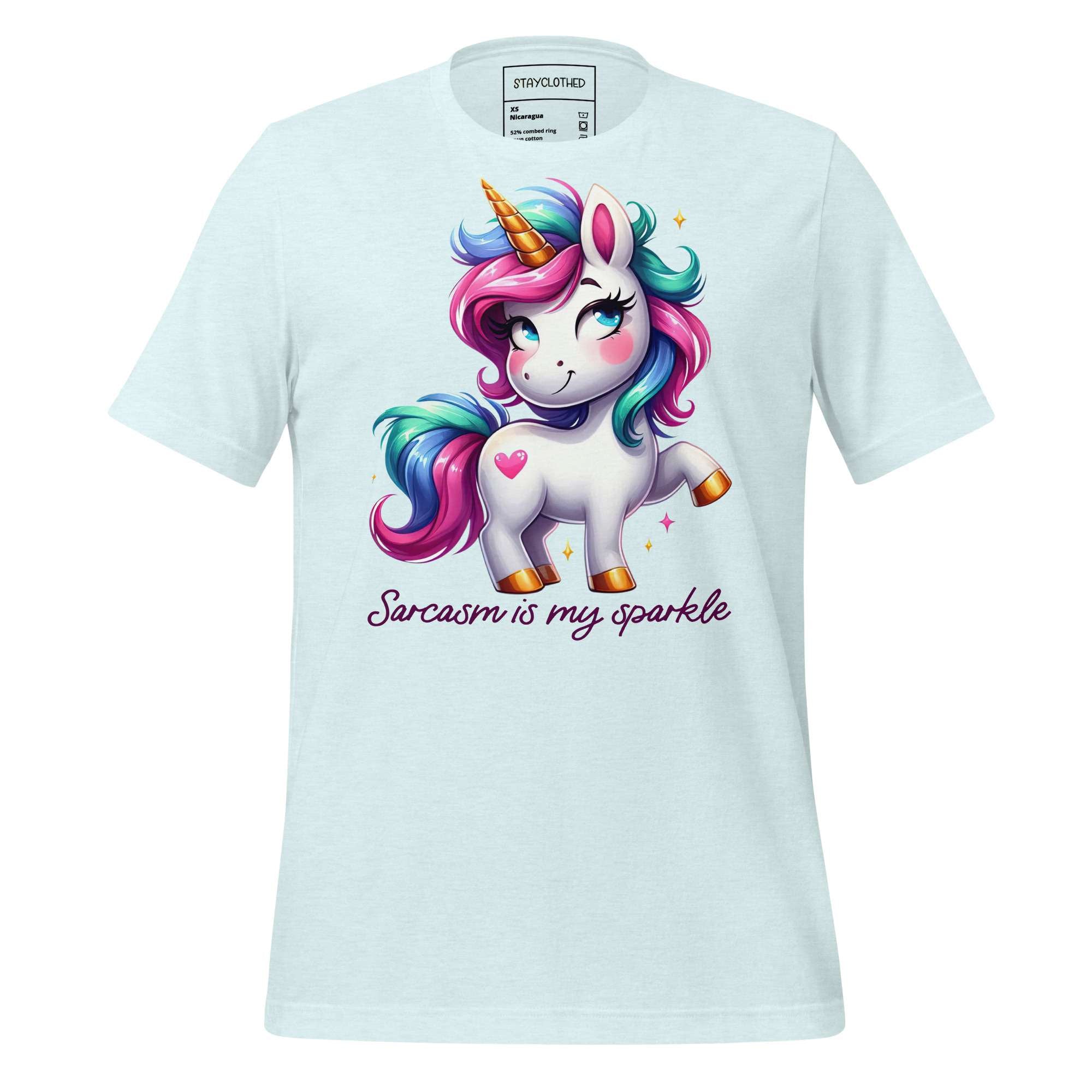 White t-shirt with a colorful unicorn graphic and text on a wooden surface, featuring the brand 'StayClothed'.