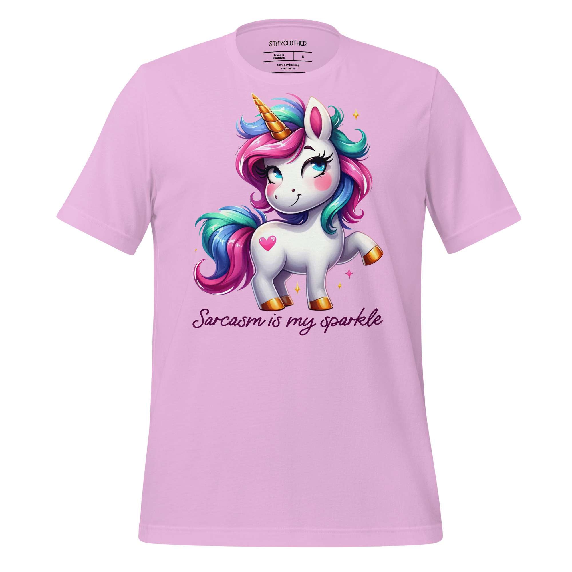 Pink t-shirt with a unicorn graphic and text on a wooden surface, featuring the brand 'StayClothed'.