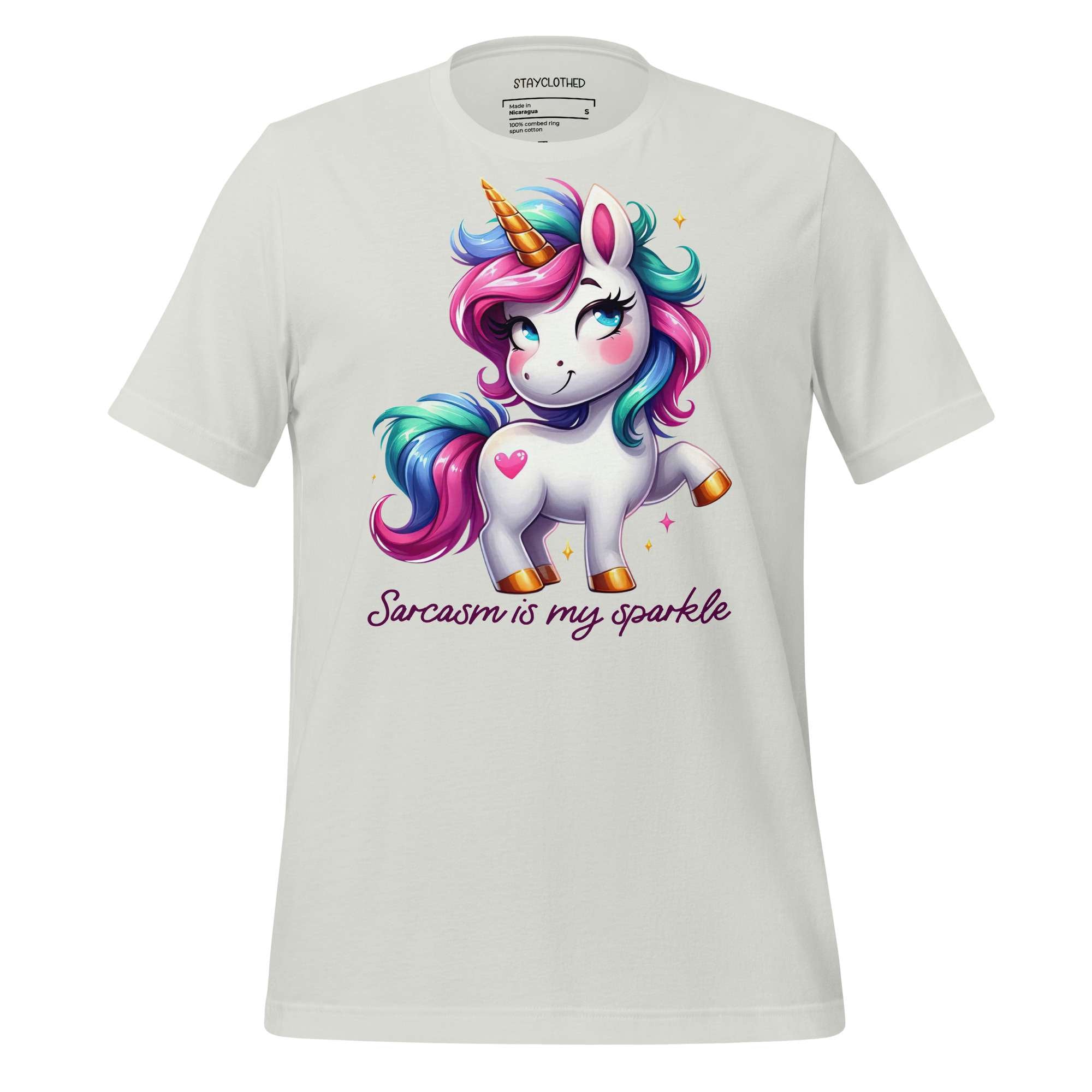 White t-shirt with a colorful unicorn graphic and text on a wooden surface, featuring the brand 'StayClothed'.