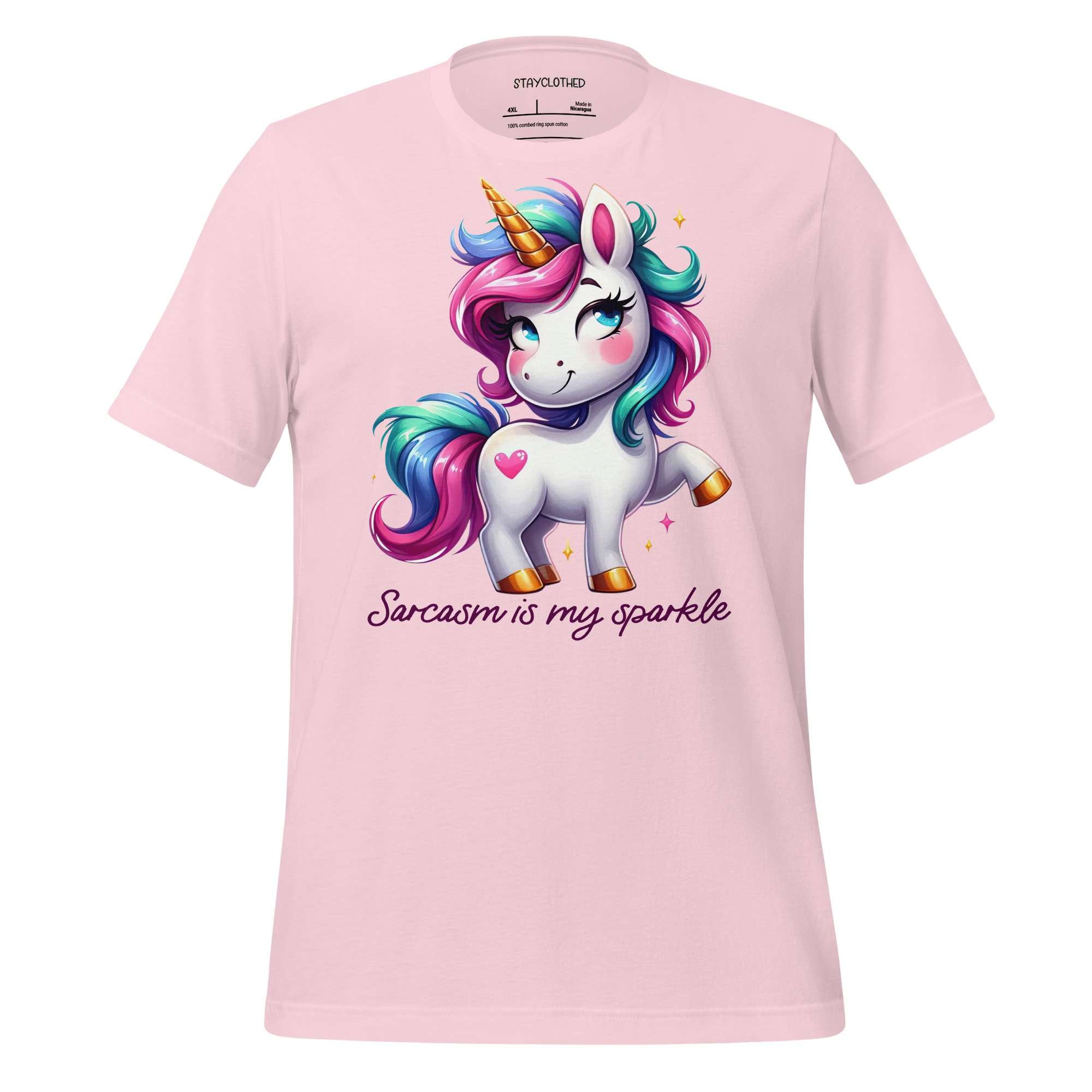 Pink t-shirt with a unicorn graphic and text on a wooden surface, featuring the brand 'StayClothed'.