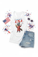 Party in the USA Raccoon Racerback Tank Top flat lay styled with denim shorts and red white and blue confetti