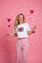 Model wearing the Pink Heart Burst Crop Top in a bright pink studio scene with pink trousers