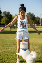 Model wearing the Proudly Pawtriotic Racerback Tank Top on grass with a small white dog