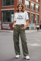 Model wearing the Stay Happy Cropped Festival Top with green trousers in a streetwear scene