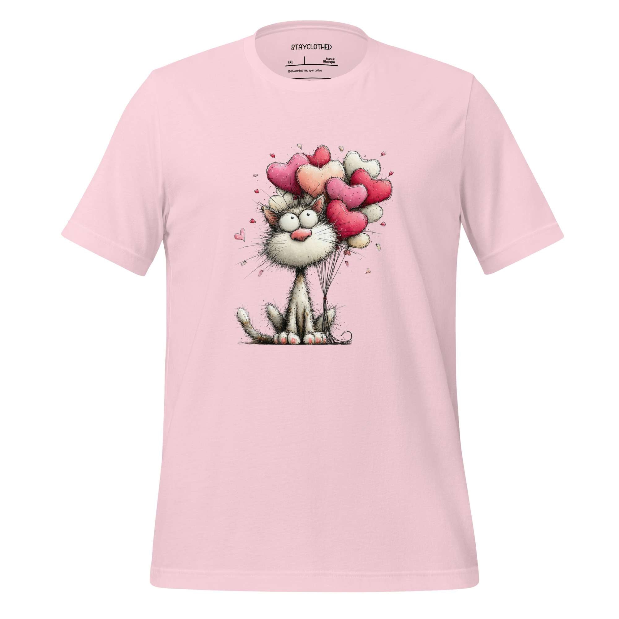 Pink t-shirt with a cat holding heart balloons design on a wooden surface, featuring the brand 'StayClothed'.