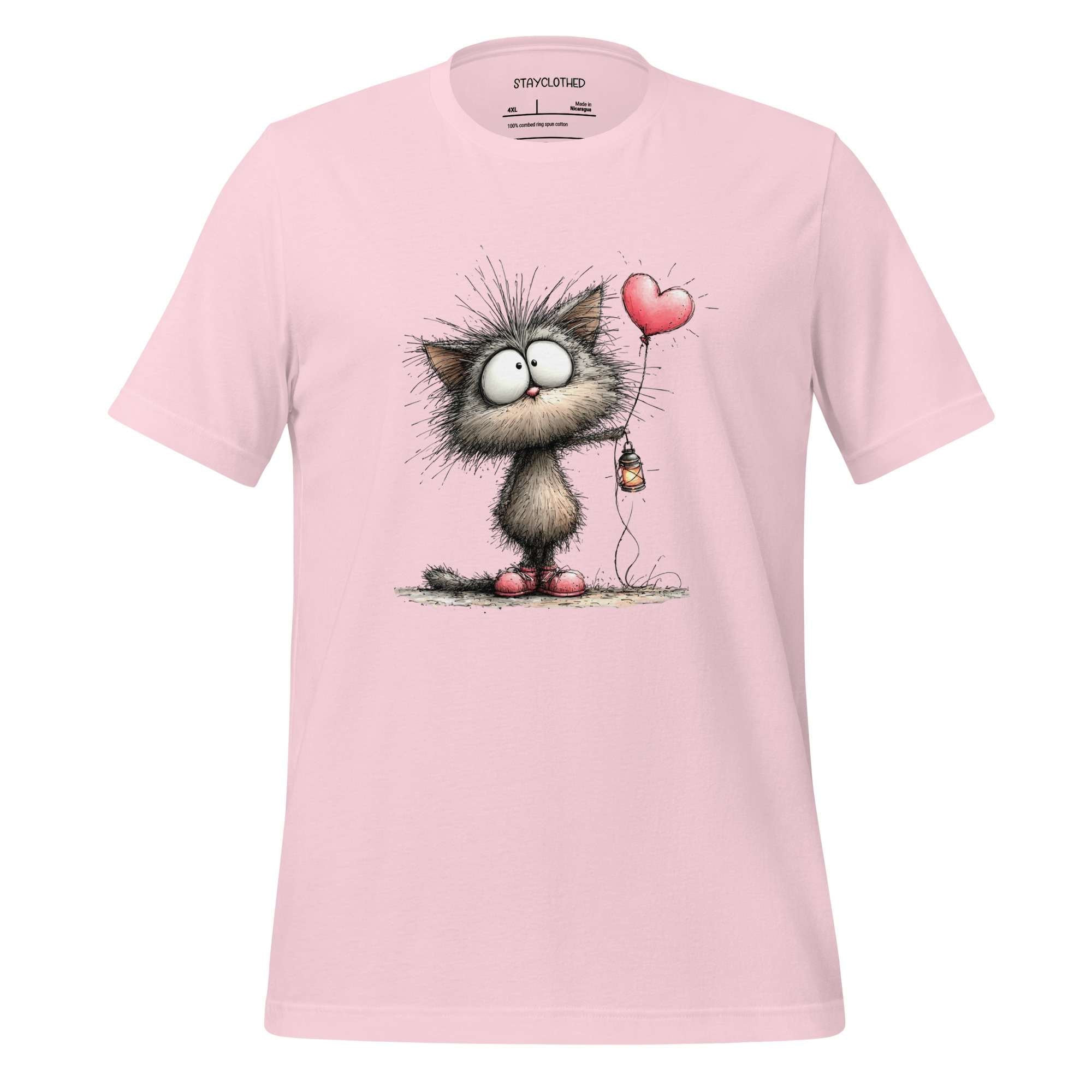 Pink t-shirt with a cartoon cat holding a heart-shaped balloon on a wooden surface, featuring the brand 'StayClothed'.
