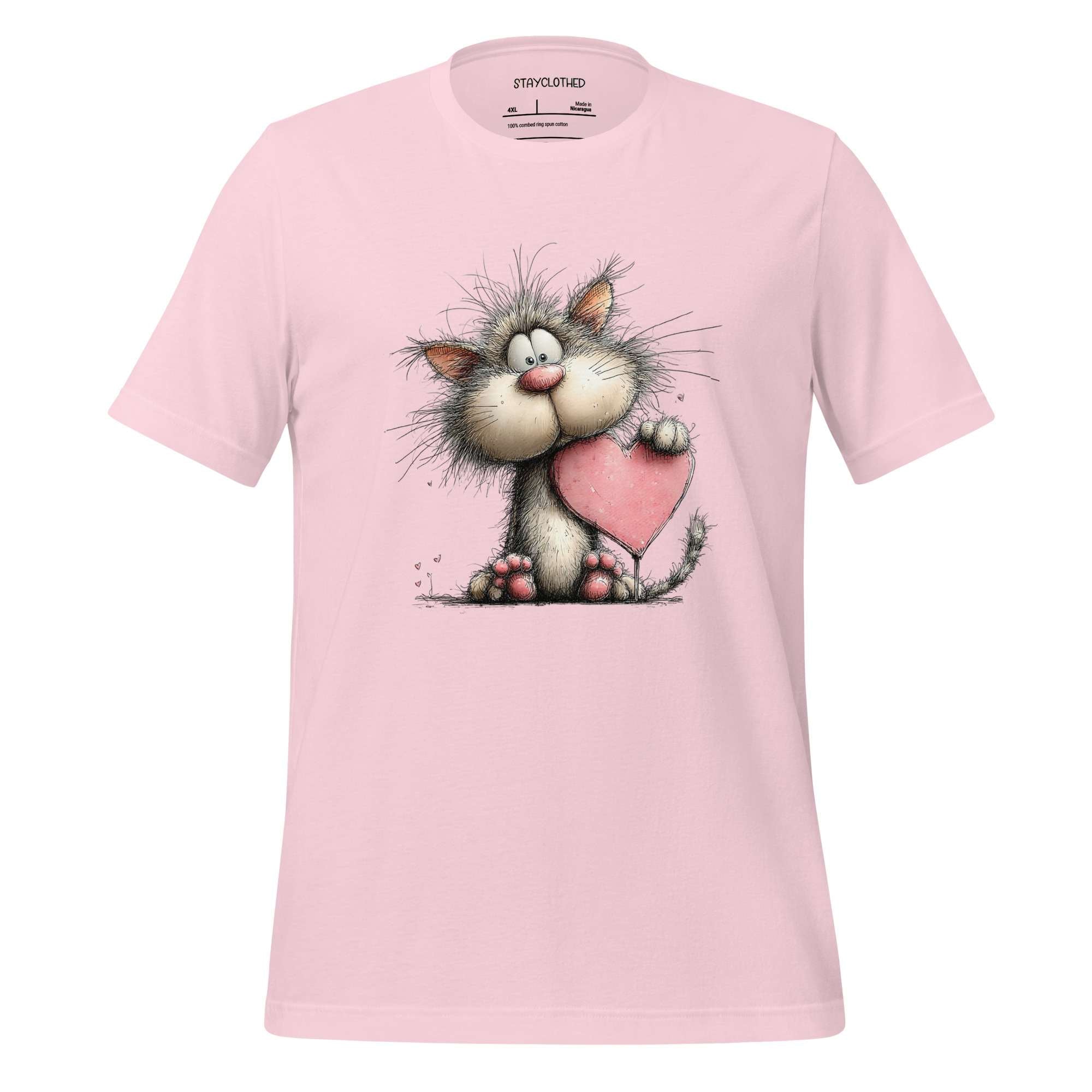 Pink t-shirt with a cartoon cat holding a heart on a wooden surface, featuring the brand 'StayClothed'.