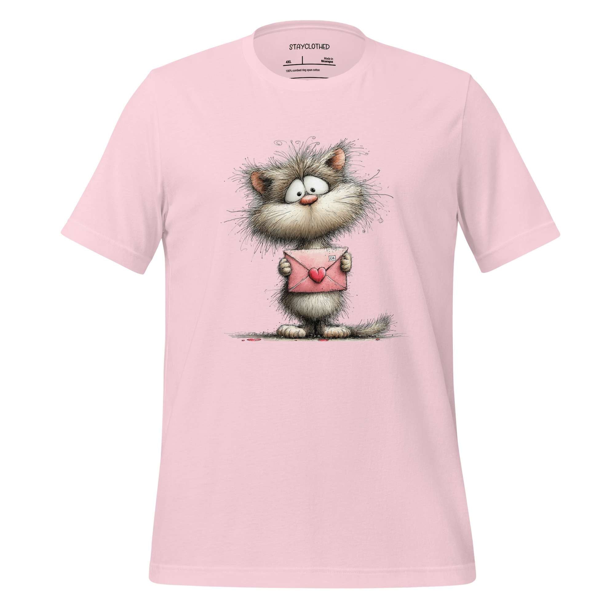 Pink t-shirt with a cartoon cat holding a heart on a wooden surface, featuring the brand 'StayClothed'.