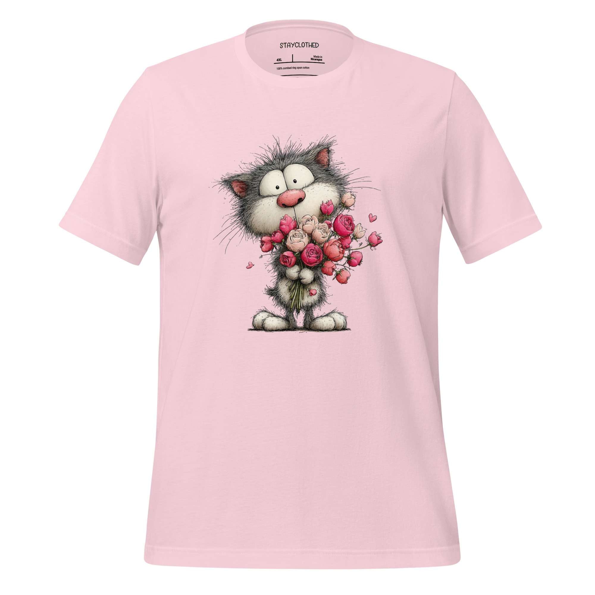 Pink t-shirt with a cartoon cat holding flowers on a wooden surface, featuring the brand 'StayClothed'.