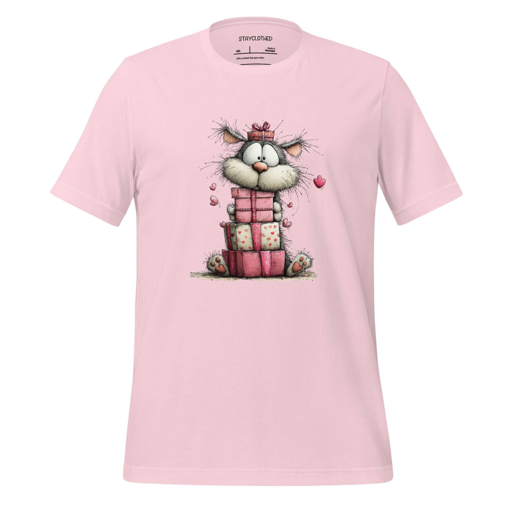 Pink t-shirt with a cartoon cat design on a wooden surface, featuring the brand 'StayClothed'.
