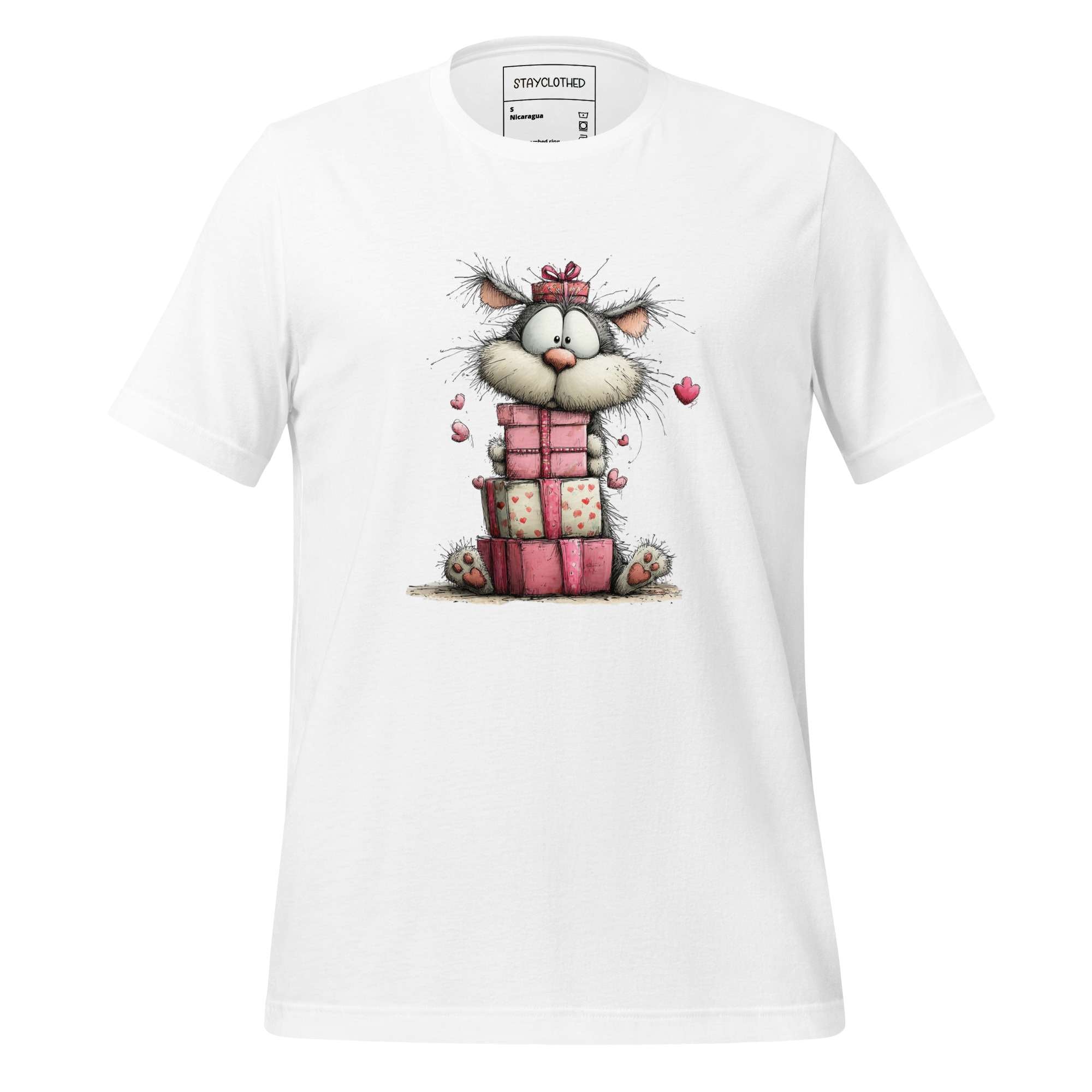 White t-shirt with a cartoon cat and presents design on a wooden surface, featuring the brand 'StayClothed'.
