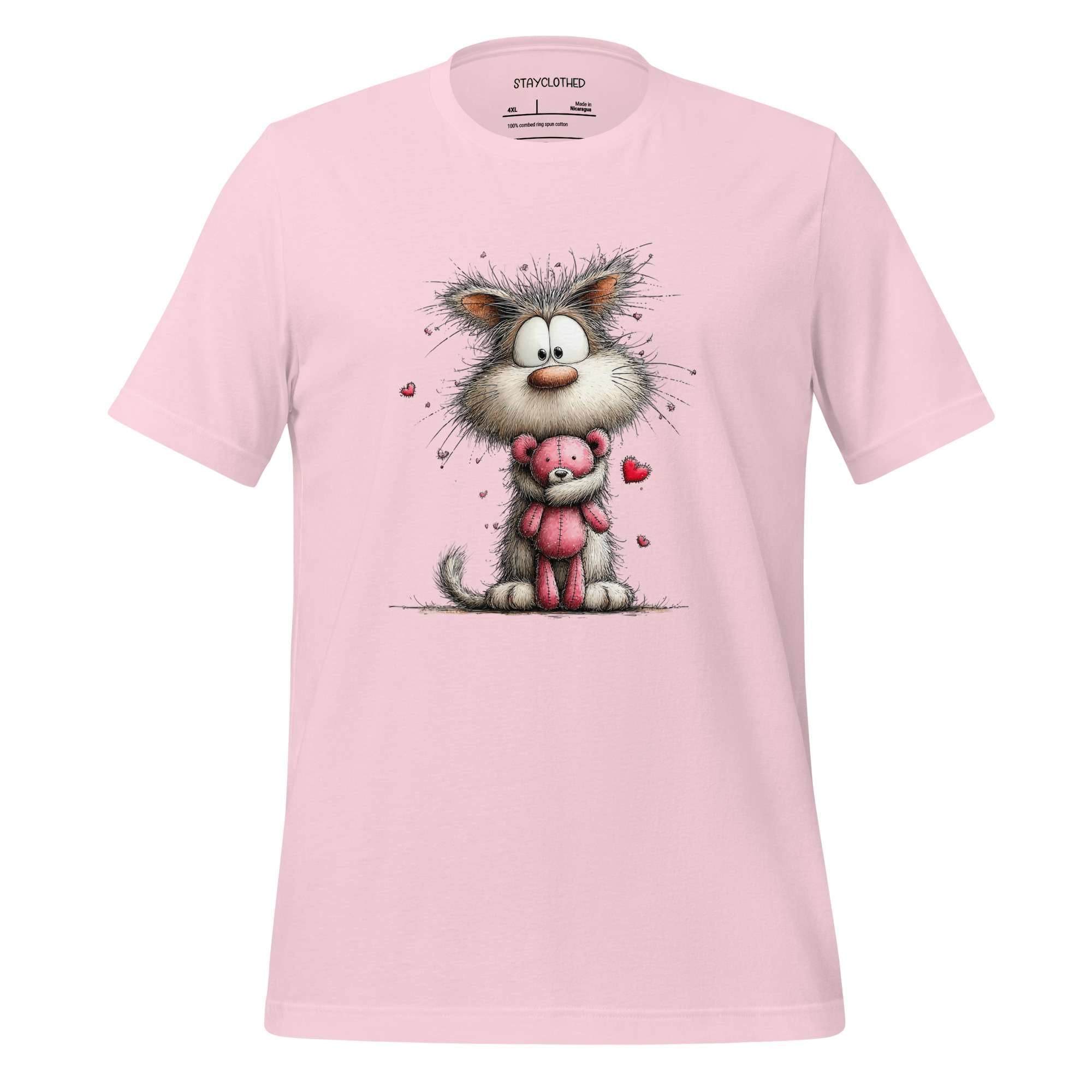 Pink t-shirt with a cartoon cat holding a pink teddy bear on a wooden surface, featuring the brand 'StayClothed'.