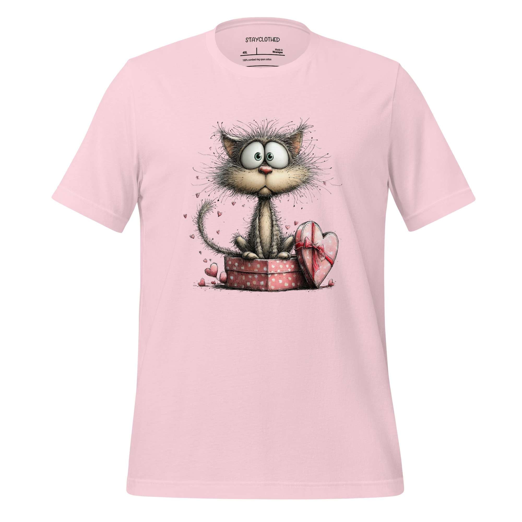 Pink t-shirt with a cartoon cat design on a wooden surface, featuring the brand 'StayClothed'.
