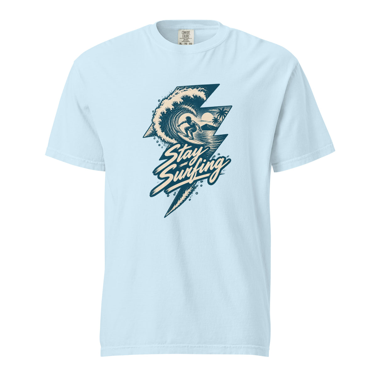 Chambray T-shirt with a vintage hand-drawn “Stay Surfing” graphic, showing a surfer inside a curling wave with palm trees.
