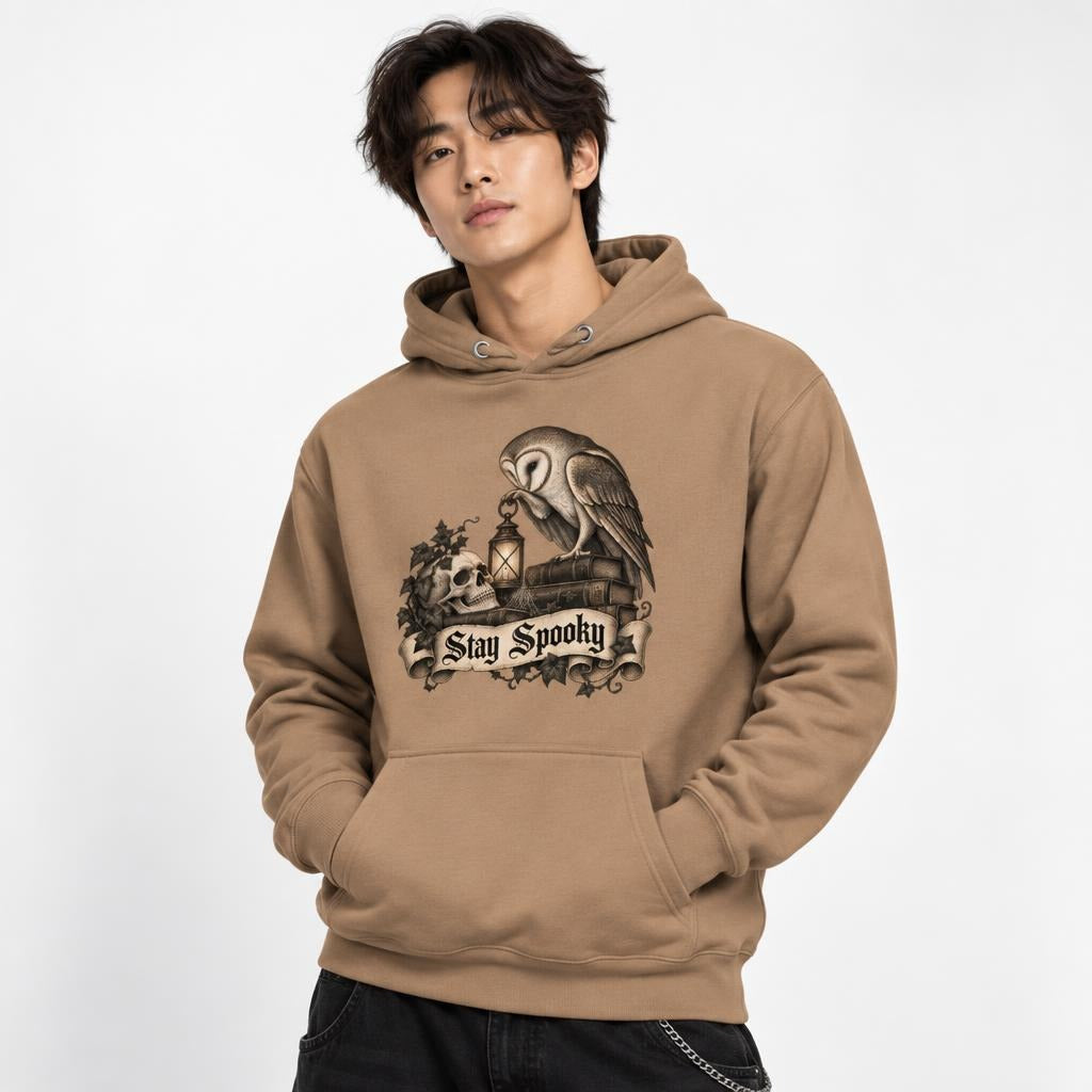 Model wearing a Latte unisex hoodie with an owl graphic, lantern, foliage, and “Stay Spooky” text on the front.