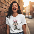 Woman wearing a white t-shirt with a cat graphic, standing against a brick wall.