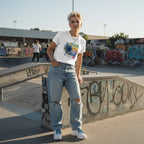White non-binary person wearing a white In April We Wear Blue autism awareness sunflower t-shirt.