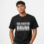 Model wearing a black T-shirt with bold distressed typography reading “YOU MIGHT BE DRUNK” in layered grey and white lettering.